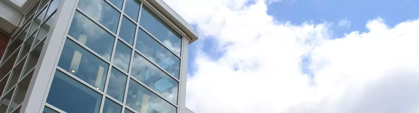 Corner of a building with large windows and sky in the background